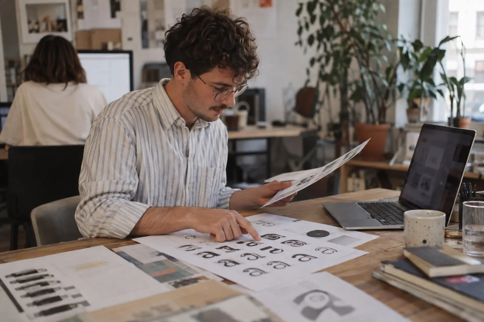 Webdesigner vergleicht ausgedruckte Schriftmuster neben einem Laptop